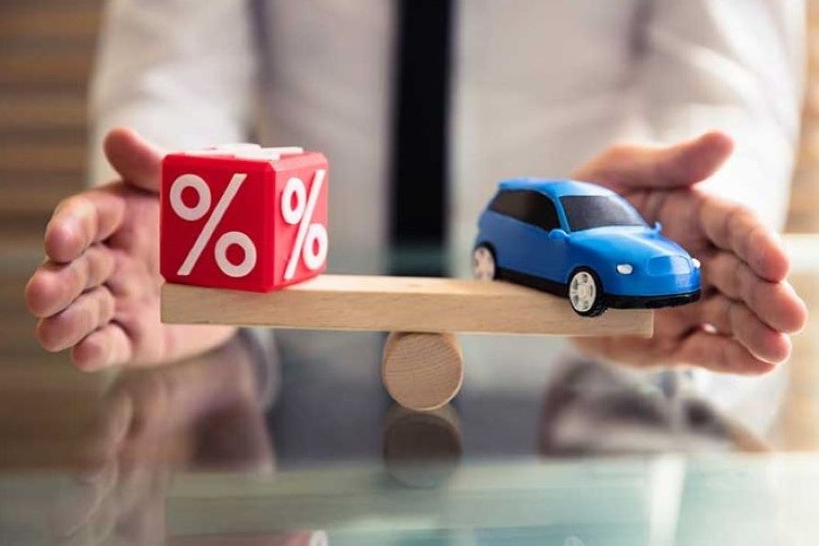 Toy car and percentage blocks balancing on a scale, representing auto financing and interest rates.